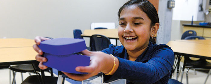a girl smiles while holding a purple box