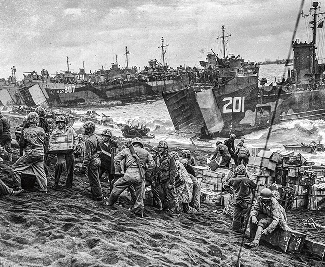 enlargeable black and white photo of a soldiers on a beach with ships behind them