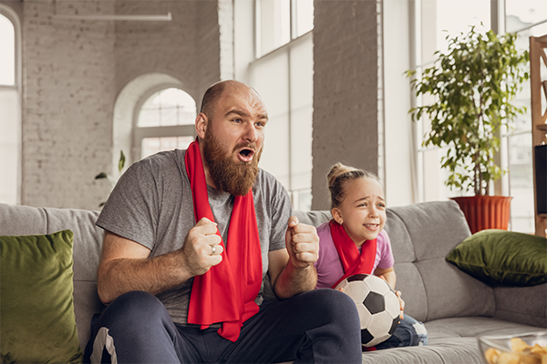 a girl and her father watching TV with a excited expression