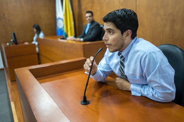 a man testifying behind a microphone in a court room 