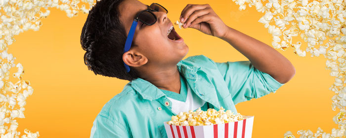 A boy dropping popcorn in his mouth
