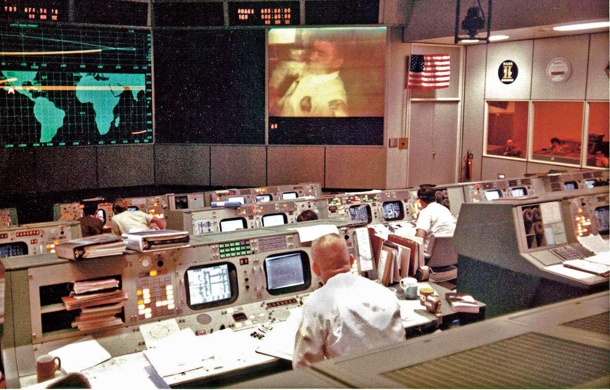 A room filled with computers and people looking at projections